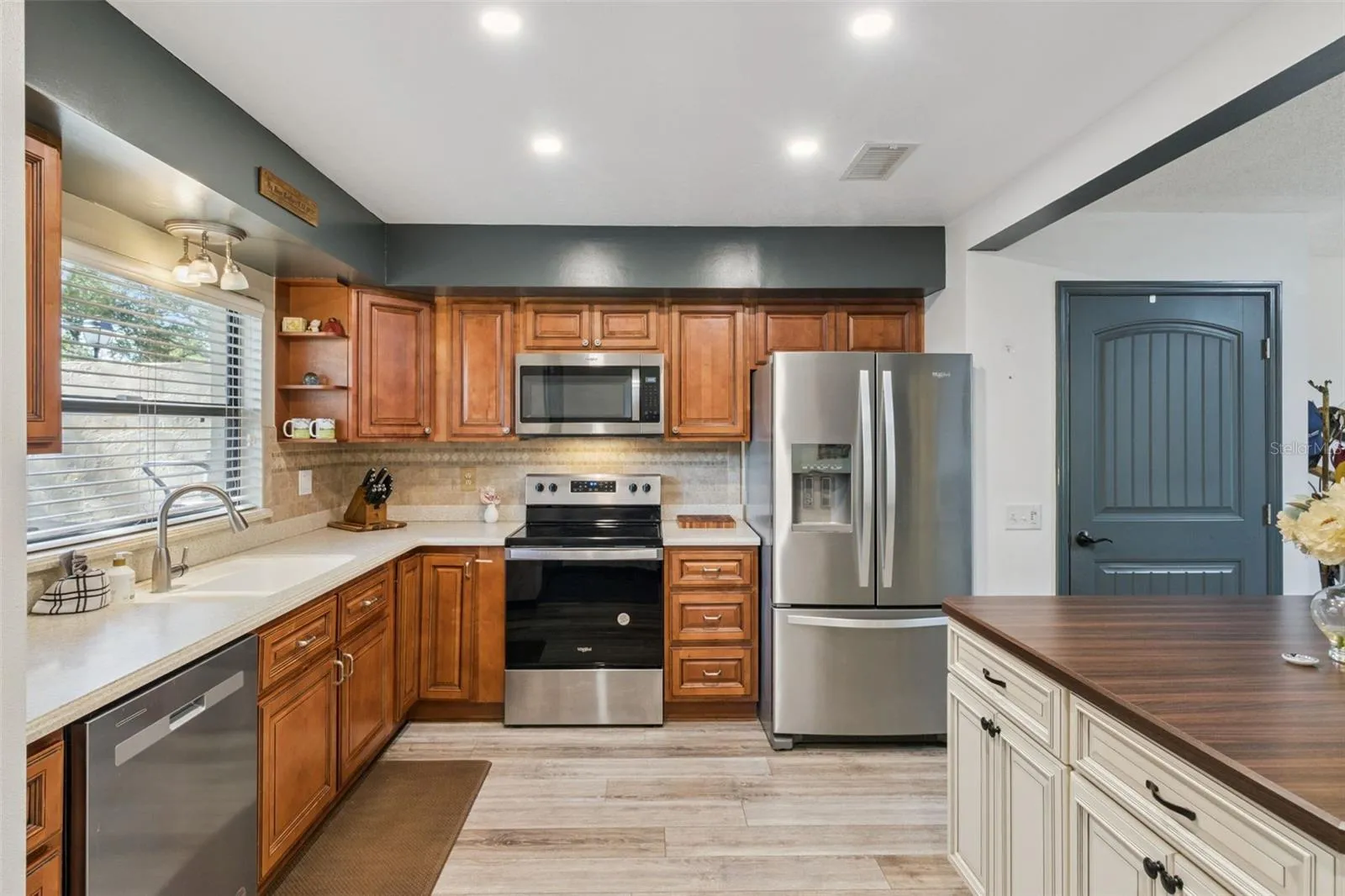 Maple wood cabinetry features Corian countertops and a tile backsplash