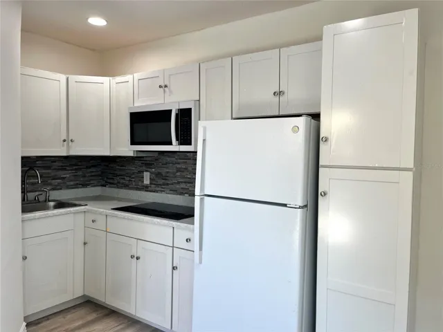 Kitchen with full size refrigerator, stove top and microwave plus storage space