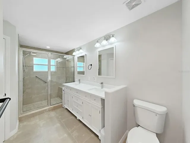 Primary En-suite bathroom.  Spacious shower has a nicely sized bench and stylish tile.  Vanity is new with double sinks. Linen closet and new toilet top it off!