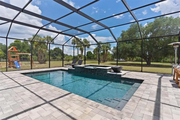 Outdoor living reaches another level w/ the spectacular screened saltwater pool & spa. Spend your days relaxing in the pool, unwind in the hot tub, or gather around one of the 2 fire pits that beautifully frame the spa area