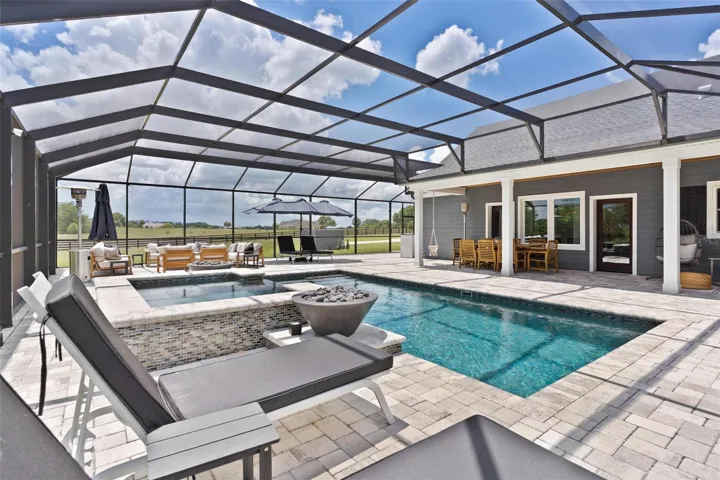 Outdoor living reaches another level w/ the spectacular screened saltwater pool & spa. Spend your days relaxing in the pool, unwind in the hot tub, or gather around one of the 2 fire pits that beautifully frame the spa area