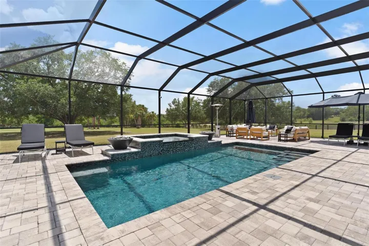 Outdoor living reaches another level w/ the spectacular screened saltwater pool & spa. Spend your days relaxing in the pool, unwind in the hot tub, or gather around one of the 2 fire pits that beautifully frame the spa area