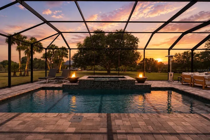 Screened Lanai brick paver salt water pool with spa framed by 2 propane firepits.