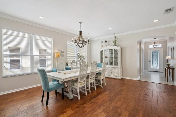 Rich hardwood flooring, soaring ceilings, crown molding, abundant natural light, and a stunning designer chandelier