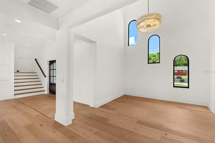 GRACIOUS DINING ROOM SHOWCASING SOARING ARCHED WINDOWS AND A DESIGNER CHANDELIER
