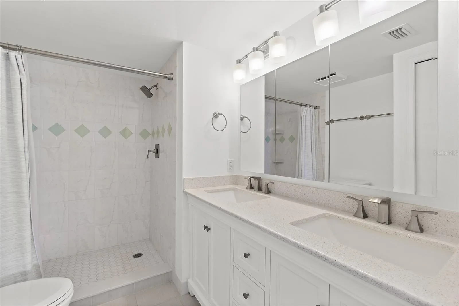 Primary bathroom with dual sink vanity, quartz countertop, and walk-in tile shower