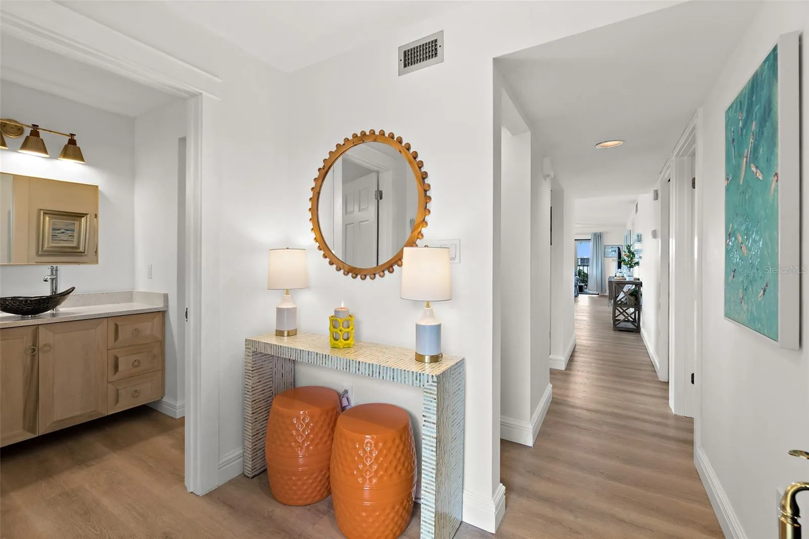 Entry foyer with powder bath, round mirror, console table, and wood-look flooring, Cocoa Beach condo