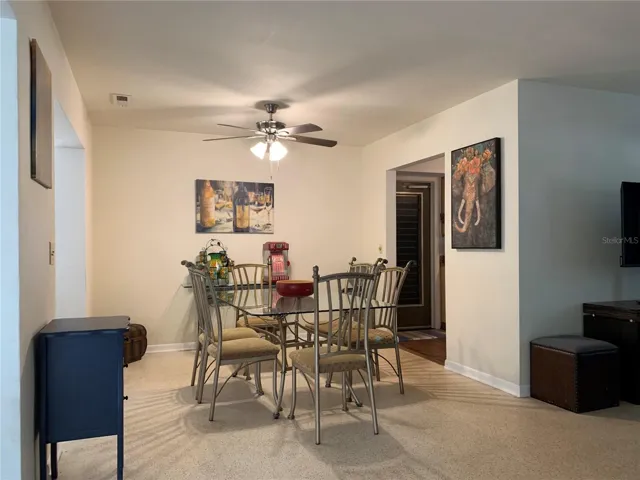 Dining area. To the left is the Florida room with the bar height tables and to the right is the doorway into the kitchen. Ceiling fans everywhere.