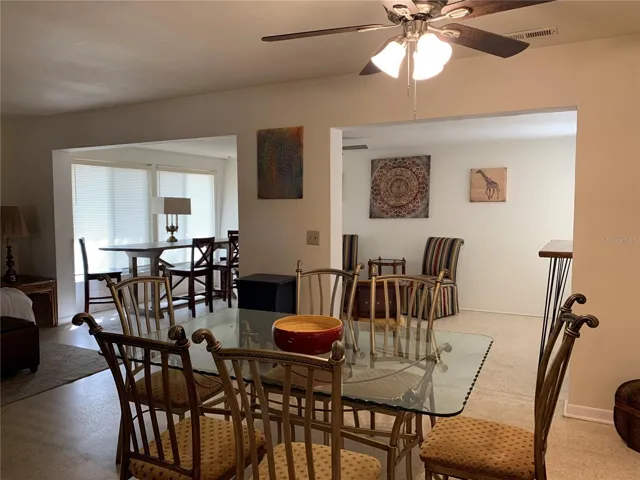 This glass-top dining set seats 6 on sturdy metal chairs. In the background you can see the Florida room with additional bar height dining and cozy conversation seating area as well.
