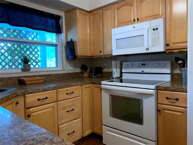 Window looks out towards the front of the house. On the counter is a knife block, two-slot toaster and cooking utensils.