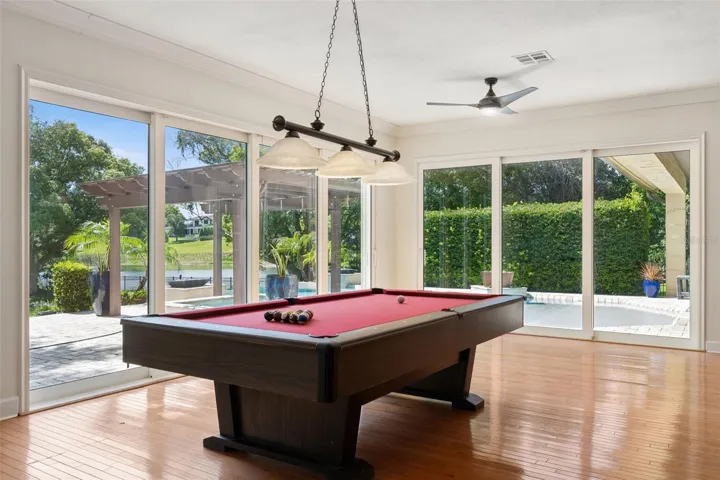 Game Room with view of the Pool and Lake.  Beautiful natural wood floor.  Sliding Energy effcient doors for the open air experience