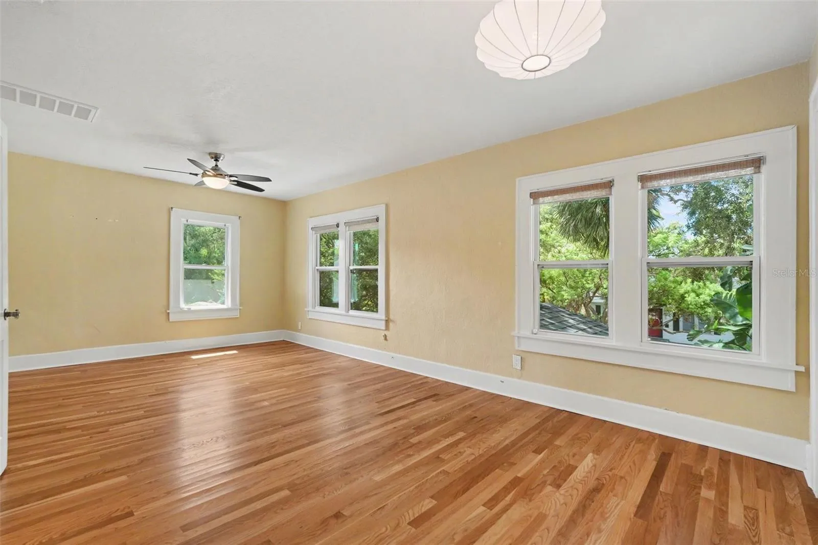 Multiple windows frame leafy neighborhood views, giving the primary bedroom a bright and peaceful feel.