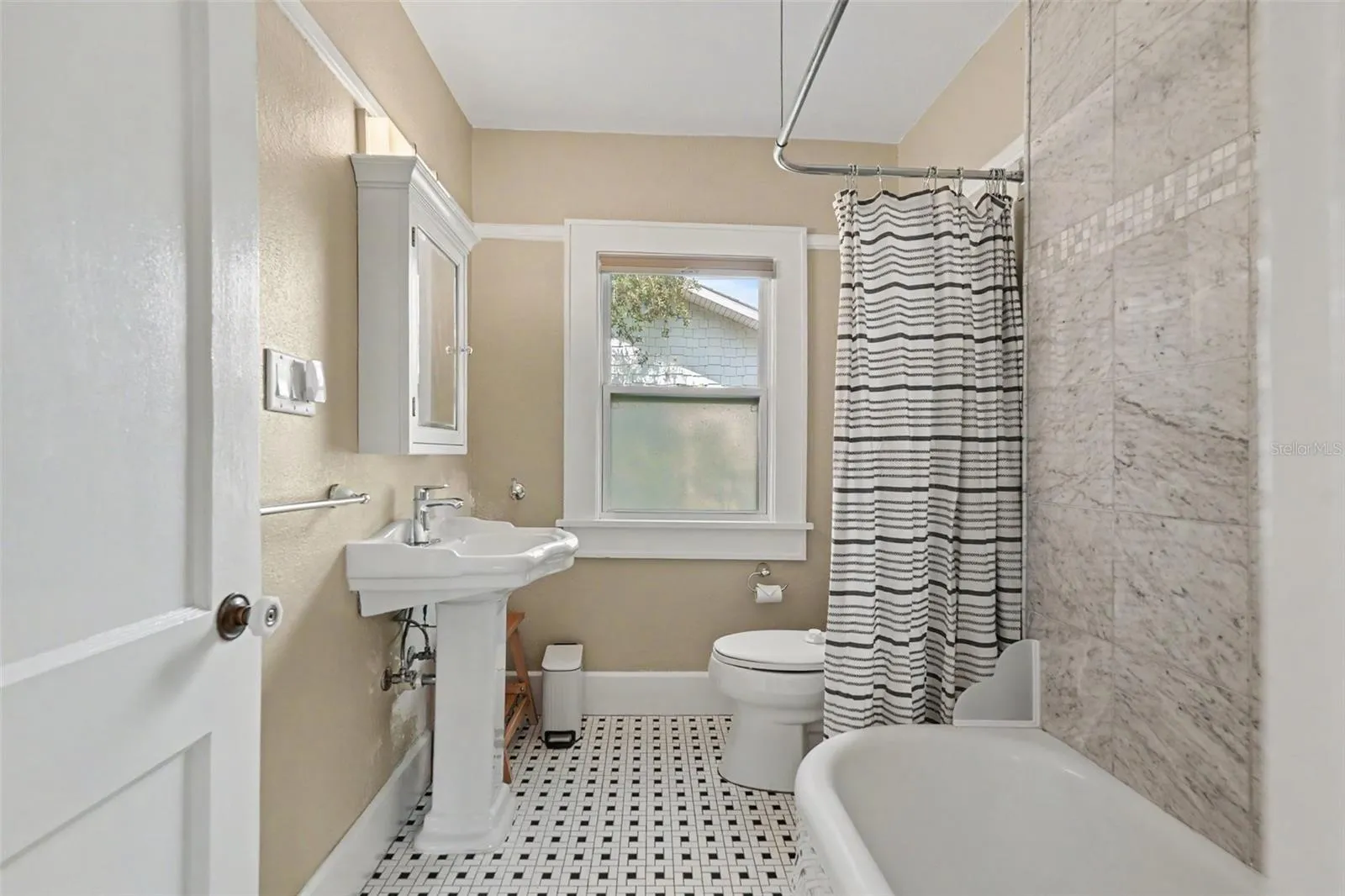 The full bathroom blends vintage character with thoughtful updates, including classic tilework, a pedestal sink, and a tub/shower combination.
