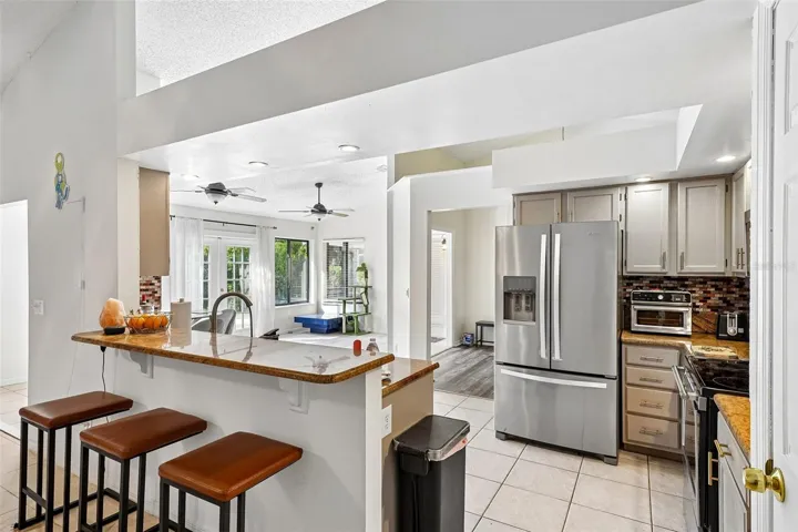 Spacious kitchen with stone countertops, ceramic tiles and vaulted ceiling.