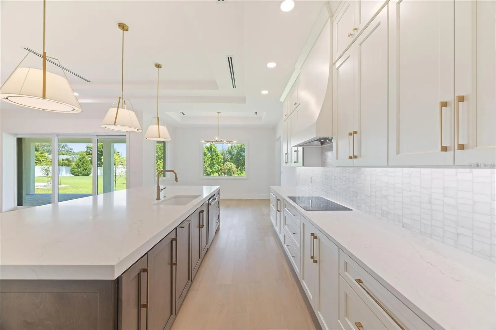 The gourmet kitchen is a true showpiece, featuring full-height custom cabinetry, an oversized 11-foot quartz island with storage on both sides, marble backsplash, GE Profile appliances, custom range hood, cooktop, wall oven, and soft-close cabinetry throughout.