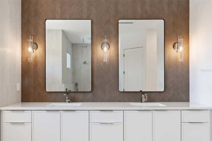 The luxurious primary suite offers a spa-inspired retreat featuring a freestanding soaking tub, oversized walk-in shower with rain head and handheld shower, premium Italian tile, designer fixtures, and thoughtful custom details throughout.