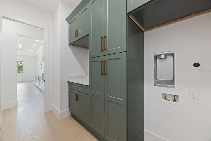 Designed with both beauty and functionality in mind, the laundry room offers elegant Shaker Ivy cabinetry, abundant storage with tall cabinets, stackable washer and dryer hookups, and a pre-plumbed sink base cabinet.