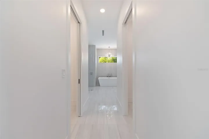 The luxurious primary suite offers a spa-inspired retreat featuring a freestanding soaking tub, oversized walk-in shower with rain head and handheld shower, premium Italian tile, designer fixtures, and thoughtful custom details throughout.