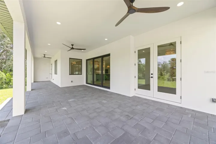 Covered paver lanai, pre-plumbed for a future outdoor kitchen, overlooking the beautifully landscaped yard with premium St. Augustine sod and mature native pine trees.