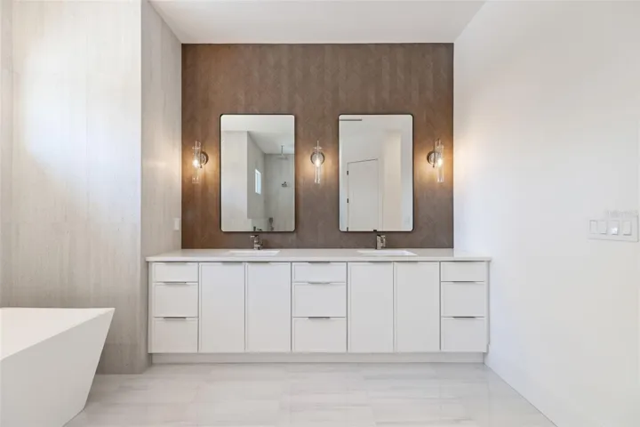 The luxurious primary suite offers a spa-inspired retreat featuring a freestanding soaking tub, oversized walk-in shower with rain head and handheld shower, premium Italian tile, designer fixtures, and thoughtful custom details throughout.