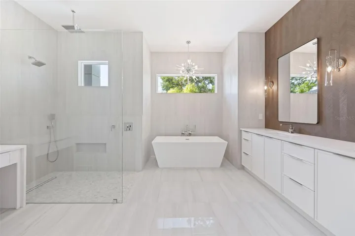 The luxurious primary suite offers a spa-inspired retreat featuring a freestanding soaking tub, oversized walk-in shower with rain head and handheld shower, premium Italian tile, designer fixtures, and thoughtful custom details throughout.