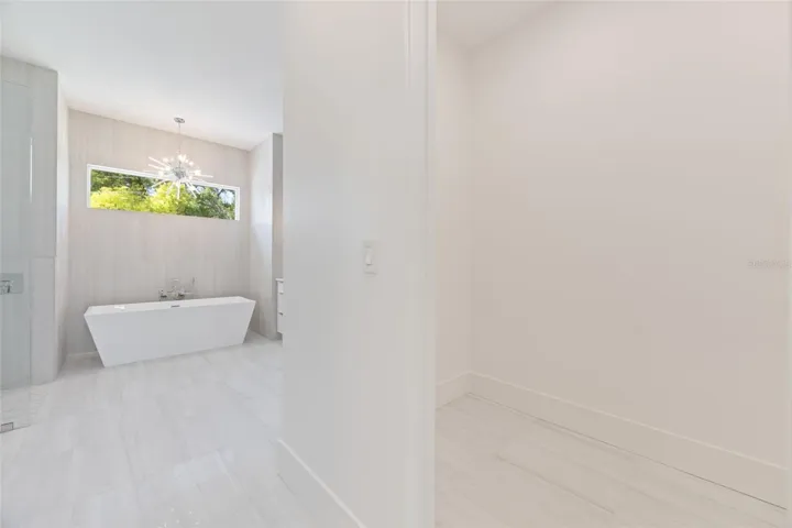 The luxurious primary suite offers a spa-inspired retreat featuring a freestanding soaking tub, oversized walk-in shower with rain head and handheld shower, premium Italian tile, designer fixtures, and thoughtful custom details throughout.