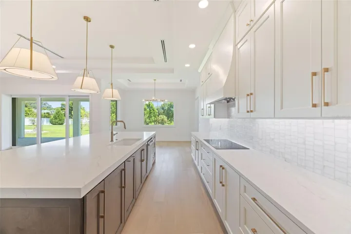 The gourmet kitchen is a true showpiece, featuring full-height custom cabinetry, an oversized 11-foot quartz island with storage on both sides, marble backsplash, GE Profile appliances, custom range hood, cooktop, wall oven, and soft-close cabinetry throughout.