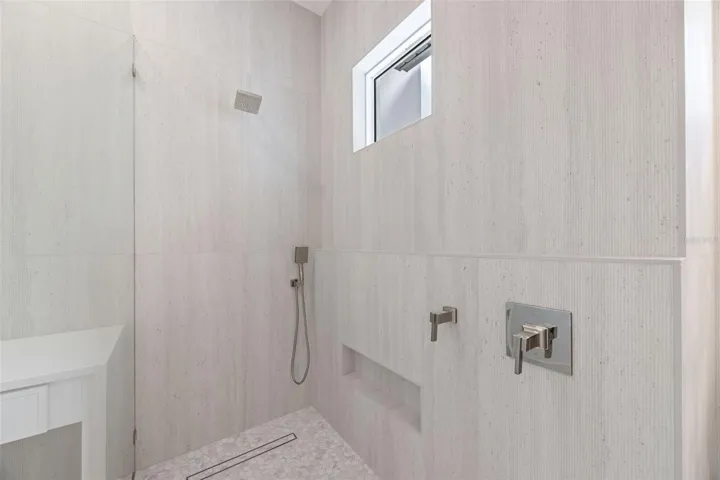 The luxurious primary suite offers a spa-inspired retreat featuring a freestanding soaking tub, oversized walk-in shower with rain head and handheld shower, premium Italian tile, designer fixtures, and thoughtful custom details throughout.