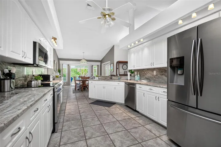 Around the corner is this amazing Kitchen. There is a breakfast bar for a casual bite or a more formal space beyond with views of the pool deck and pond.