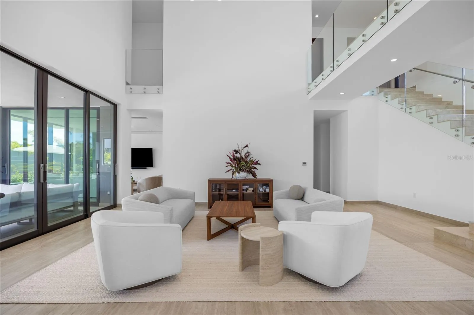 The home's impressive entrance opens to a light-filled formal living room featuring soaring ceilings and expansive windows.