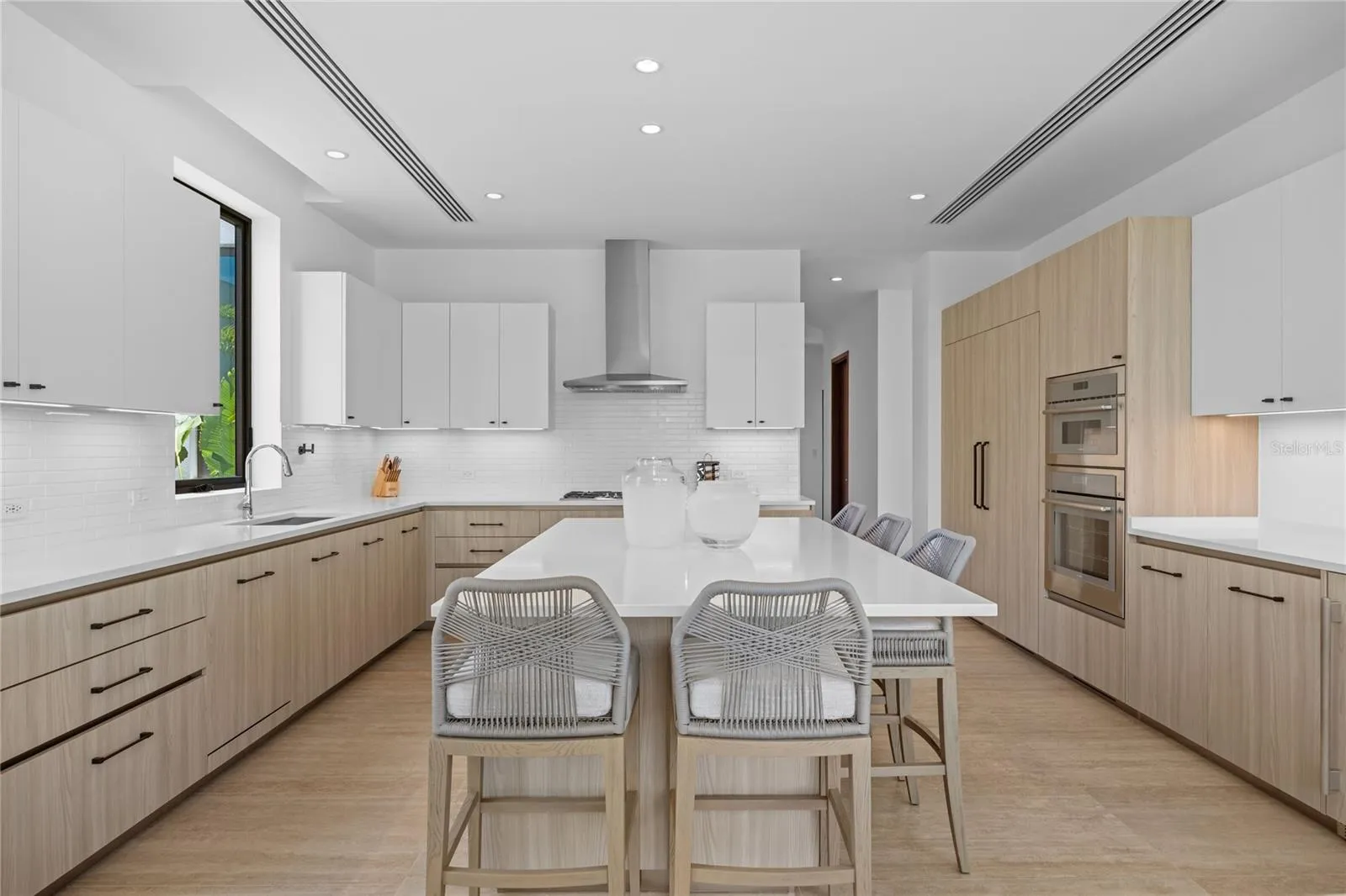 At the heart of the home is the gourmet kitchen, appointed with premium Thermador appliances, light custom cabinetry, a gas cooktop, and a large island that flows seamlessly into the family room and outdoor living areas.