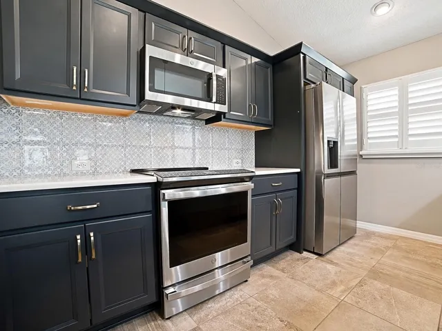 LOVELY KITCHEN WITH SLATE GRAY CABINETRY AND CHAMPAGNE BRASS HARDWARE; DECORATIVE TILE BACKSPLASH. ALL LOWER CABIINETS OFFER UPPER AND LOWER PULLOUT DRAWERS.