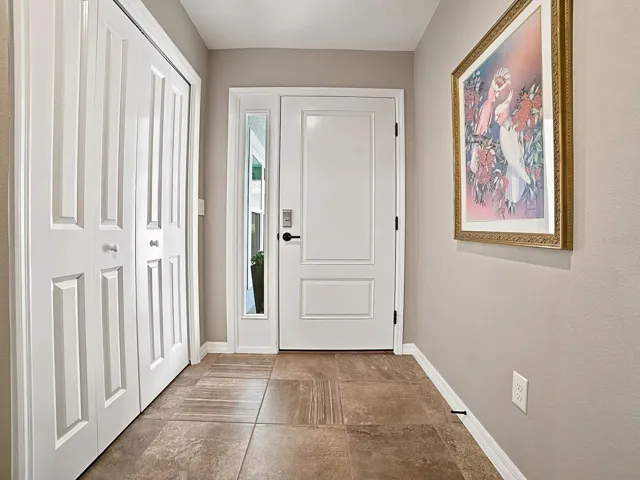 LOVELY FOYER WITH LARGE COAT CLOSET AND TILE FLOORING.