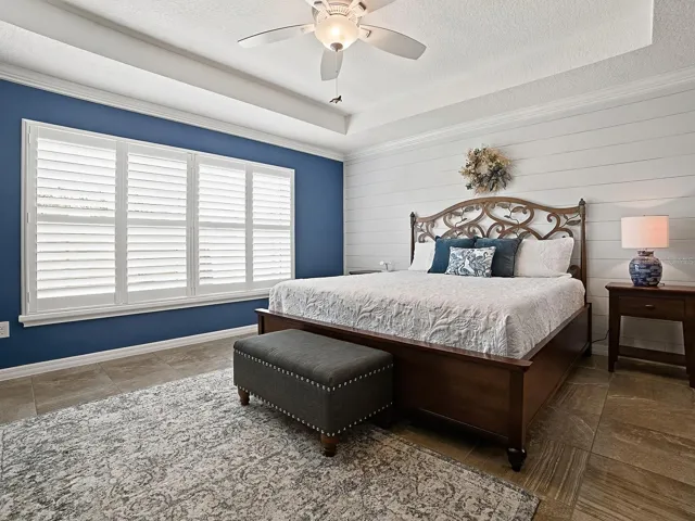 PRIMARY BEDROOM WITH TRAY CEILING AND BEADBOARD ACCENT WALL.