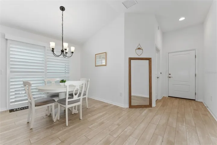 Dining area with hallway access and sliding glass door with shutters to the side patio.