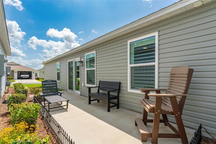 Concrete side patio and front corner exterior with maintained landscaping.