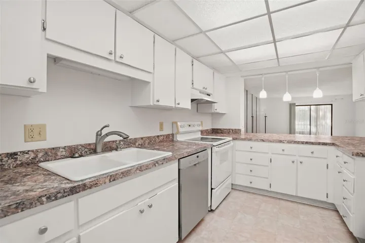 Generous cabinet storage, expansive counter space, and a pass-through accented by three pendant lights create a kitchen that's both functional and inviting.