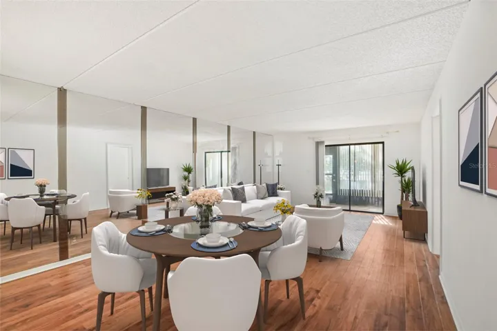 Designed to Feel Open. Continuous laminate flooring, a mirrored accent wall, and sliding glass doors to the screened lanai create an airy, inviting main living space.