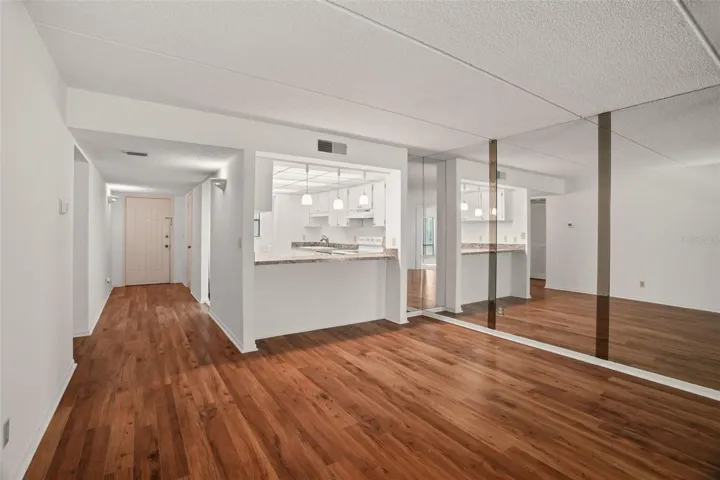 Open and Connected. A breakfast bar with three pendant lights defines the kitchen without closing it off, while the mirrored dining wall reflects natural light and enhances the sense of space.