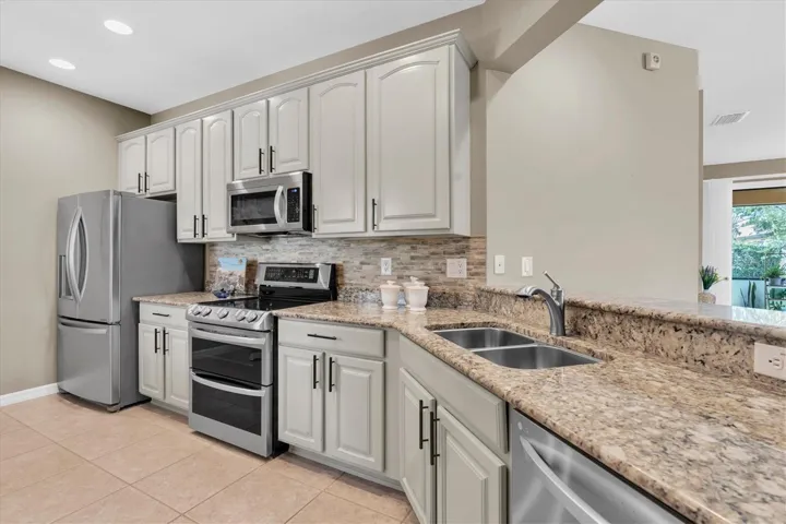 Updated kitchen with glass tile backsplash, granite counters, light modern  cabinets and hardware, new stainless appliances.