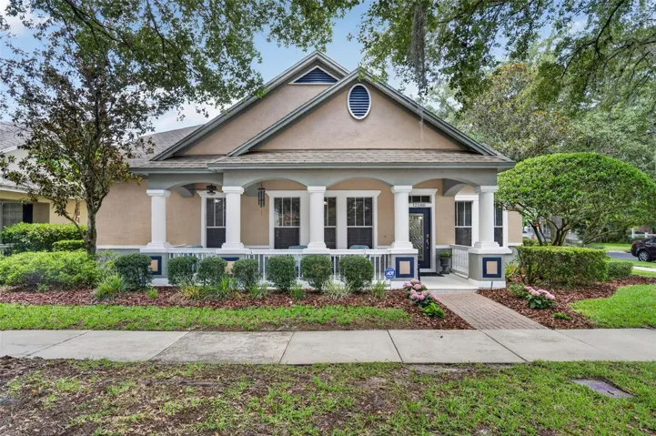 Charming front elevation with an expansive covered front porch and mature landscaping.