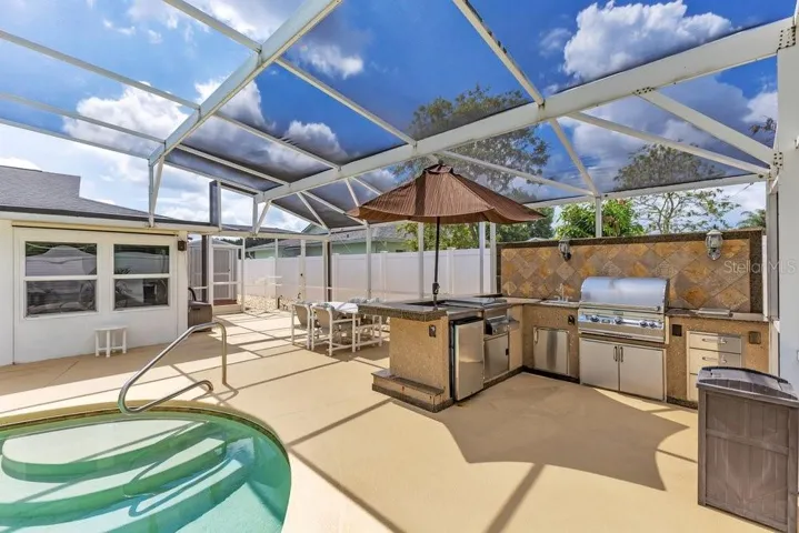 Outdoor kitchen featuring grill, refrigerator & beverage center