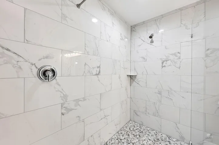 The Primary EN SUITE BATH is complete with dual sinks, stone countertops, and a stunning OVERSIZED GLASS-ENCLOSED TILED SHOWER.