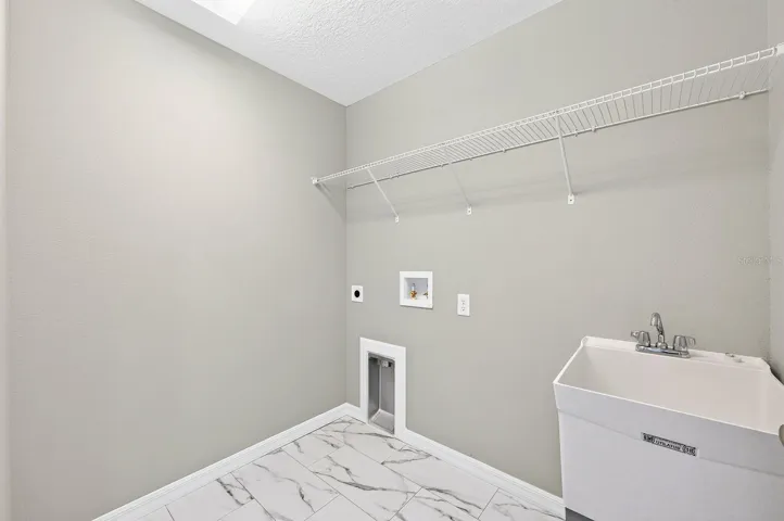 A CONVENIENT LAUNDRY ROOM includes a utility sink and ample space for a washer and dryer.