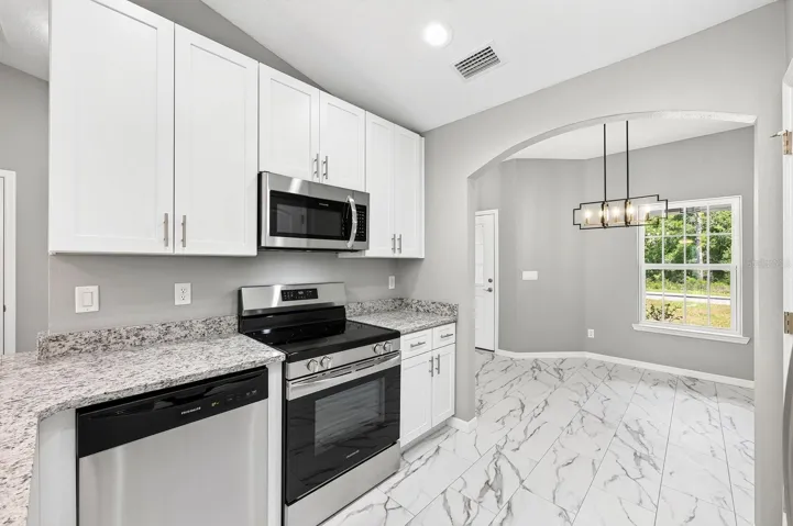 The Kitchen is beautifully appointed with white cabinetry, STONE COUNTERTOPS, stainless steel appliances, a breakfast bar, and a closet pantry, offering both style and functionality.