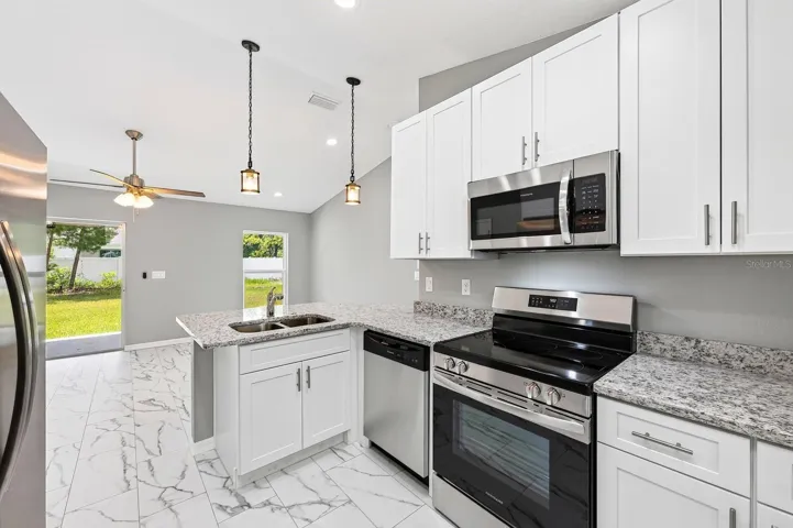 The Kitchen is beautifully appointed with white cabinetry, STONE COUNTERTOPS, stainless steel appliances, a breakfast bar, and a closet pantry, offering both style and functionality.