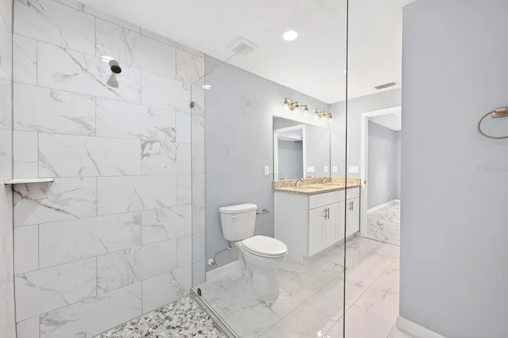 The Primary EN SUITE BATH is complete with dual sinks, stone countertops, and a stunning OVERSIZED GLASS-ENCLOSED TILED SHOWER.