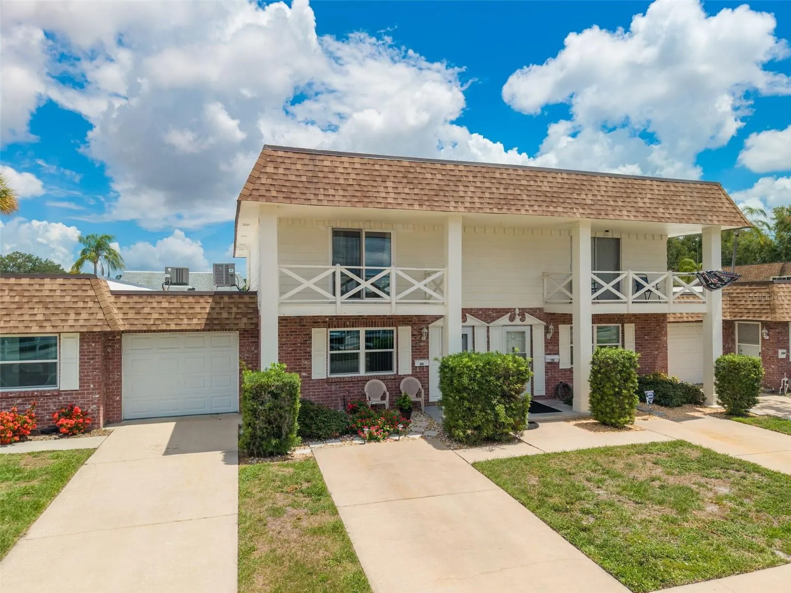 Beautiful brick-clad townhome-style condo with front outdoor porch and upper balcony.