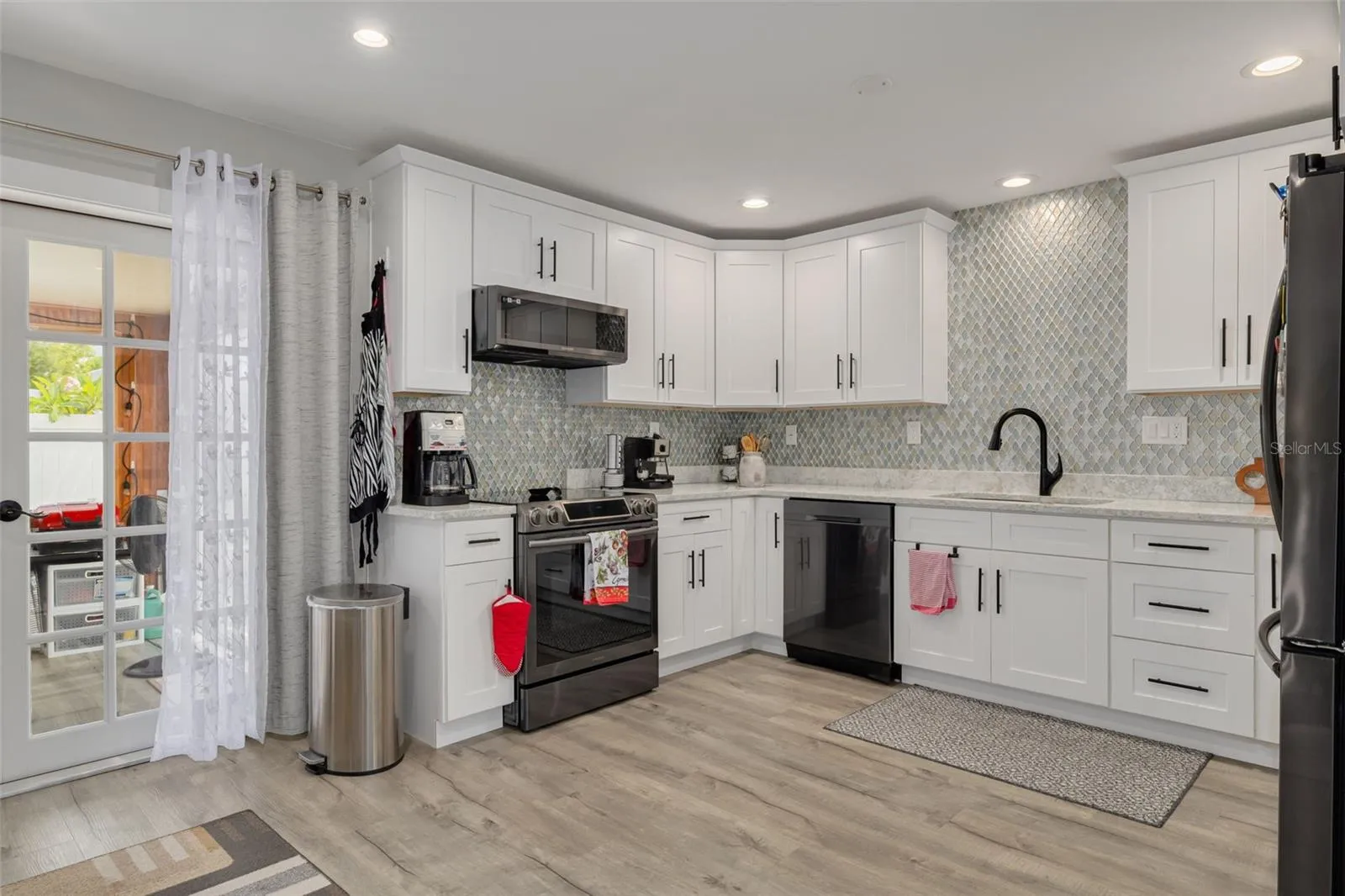 Beautifully remodeled kitchen with recessed lighting, hardwood cabinets, stone counterops, full tile backsplash (can easily add two wood accent shelves above sink), and printproof black stianless appliances.