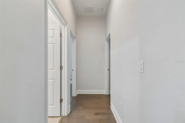 Hallway to guest full bath and two guest rooms